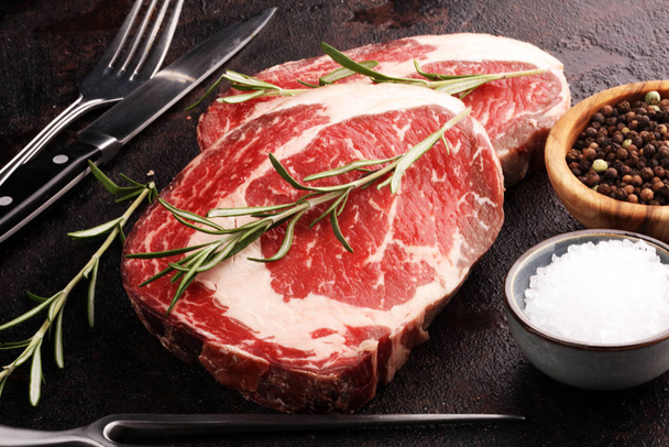 Raw fresh meat Ribeye Steak, seasoning and meat fork on rustic b - Photo, Image