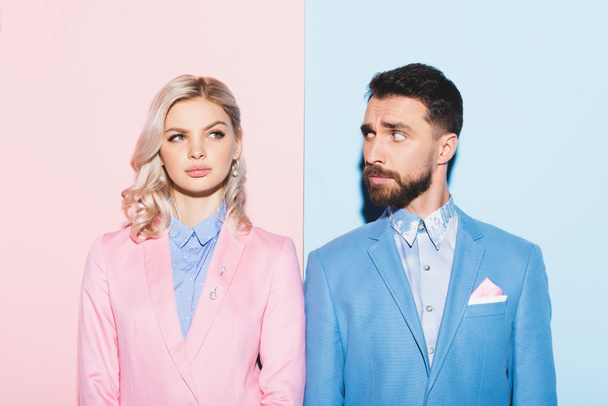 dreamy woman and handsome man looking at her on pink and blue background  - Photo, Image