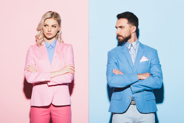 sad woman and handsome man with crossed arms on pink and blue background  - Fotografie, Obrázek