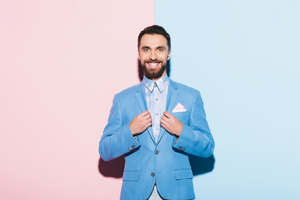 smiling man looking at camera on pink and blue background  - Valokuva, kuva