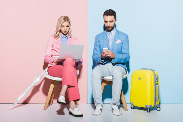 vrouw met laptop en knappe man met behulp van smartphone op roze en blauwe achtergrond  - Foto, afbeelding