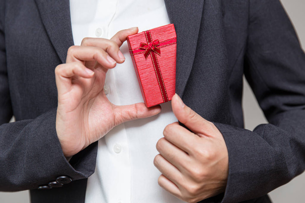 Businessman pulls a gift box out of his suit for giving their company worker for year end big bonus. - 写真・画像