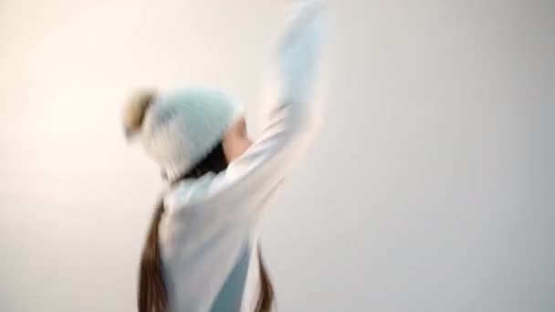 cool girl in stylish sweater dances on light background - Felvétel, videó