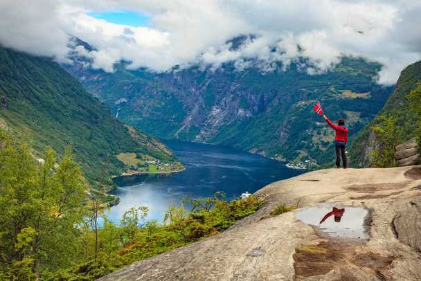 Tourist over Geirangerfjord holds norwegian flag - Foto, Imagen