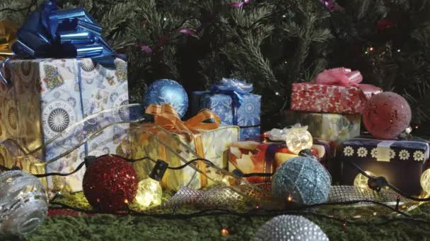 Cute Christmas Magic. The camera moves slowly along a variety of gift boxes decorated with glittering bows, Christmas tree decorations and sparkling garlands - Materiaali, video