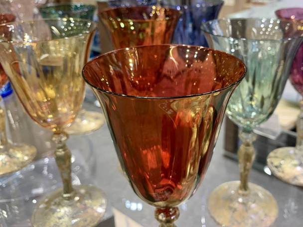 Mağazadaki bir rafta renkli şarap bardakları. Şeffaf camdan yapılmış içecekler için cam eşyalar. Tatil için kristal bardaklar. - Fotoğraf, Görsel