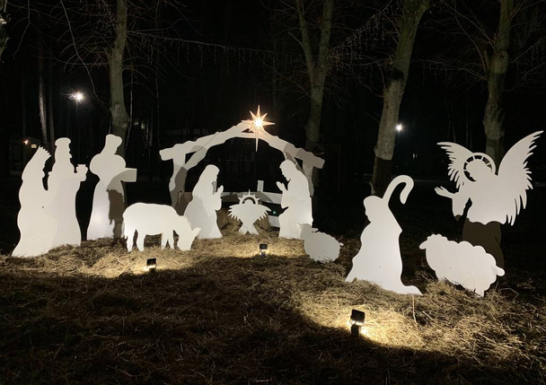 管理者のクリスマスの文字。暗い背景に公園のクリスマスの装飾。バックライト付きのネイティブシーン。概念:聖書のクリスマス文字. - 写真・画像