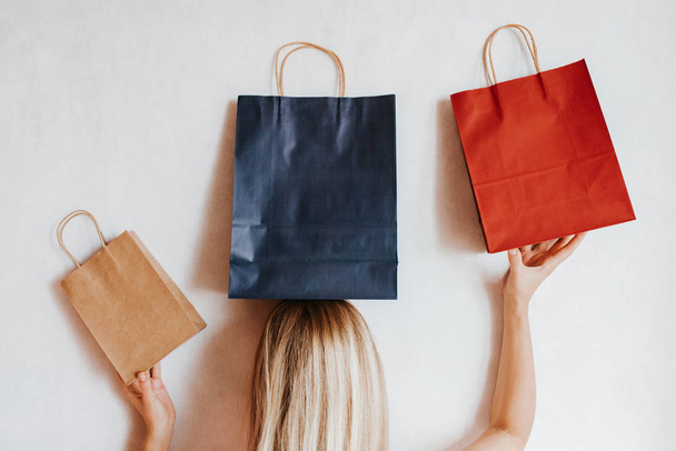 Happy woman holding shopping package on her head. Paper bag. Sale in store. Fashion shop creative advertisement. Customer buy present. Black friday sale. Holiday special offer, discount. Season deal - Foto, Imagen