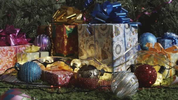 Holiday is Coming. The camera moves slowly along a variety of gift boxes decorated with glittering bows, Christmas tree decorations and sparkling garlands - Filmati, video