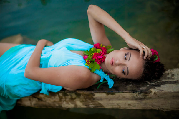 weibliches Model in blauem Kleid und Bühnenschminke posiert im Wasser - Foto, Bild