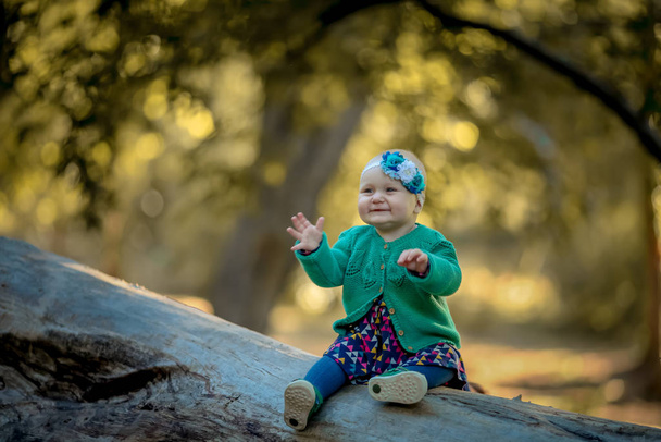 Menina sentada em um tronco e sorrindo curtindo a vida
 - Foto, Imagem