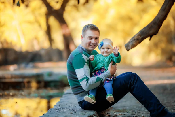 Щасливий молодий батько обіймає свою маленьку дочку в листяному зеленому лісі
 - Фото, зображення