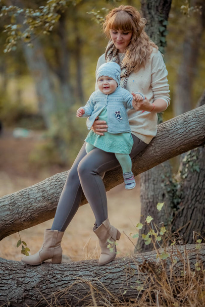 Έξω μαμά και το μωρό το φθινόπωρο στο δημόσιο πάρκο για μια βόλτα. - Φωτογραφία, εικόνα