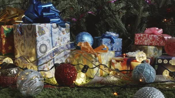 Holiday Traditional Decorations and Gifts. The camera moves slowly along a variety of gift boxes decorated with glittering bows, Christmas tree decorations and sparkling garlands - Filmati, video