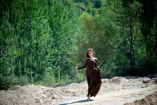 joven mujer delgada caminando en camino arenoso sobre fondo de madera
 - Foto, imagen