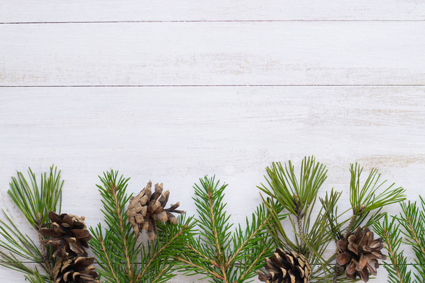 Branches of fir tree, pines cones on white wooden background - Photo, Image