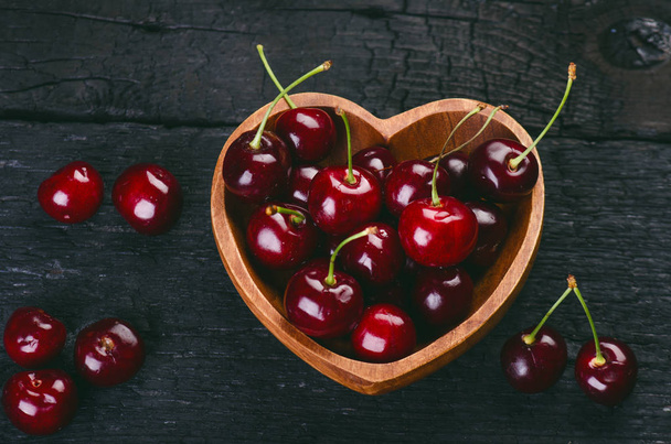 Cherries on a black table.. Natural wooden burnt table. Fresh food concept. Fruit. Summer time - Foto, imagen
