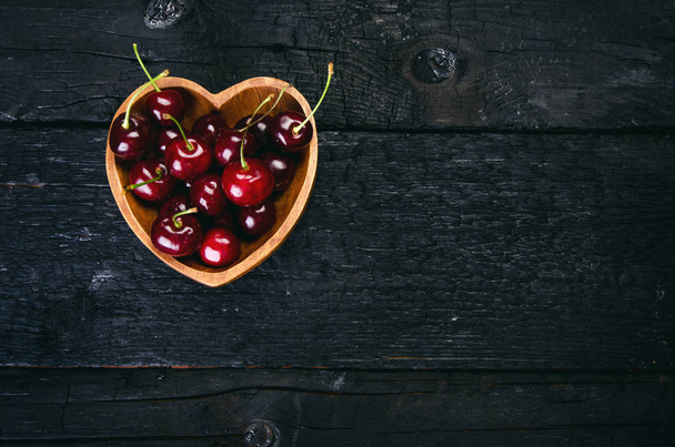 Cherries on a black table.. Natural wooden burnt table. Fresh food concept. Fruit. Summer time - Foto, Bild