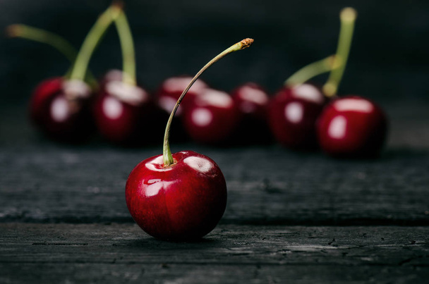 Cherries on a black table.. Natural wooden burnt table. Fresh food concept. Fruit. Summer time - 写真・画像