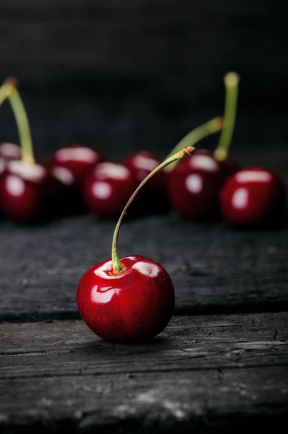 Cherries on a black table.. Natural wooden burnt table. Fresh food concept. Fruit. Summer time - 写真・画像