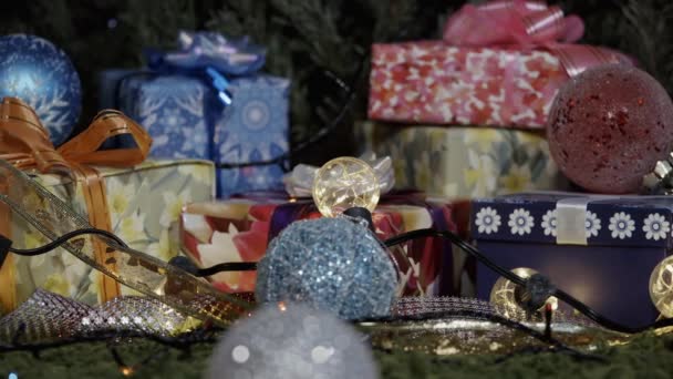 Gifts and Christmas Decorations. The camera moves slowly along a variety of gift boxes decorated with glittering bows, Christmas tree decorations and sparkling garlands - Video