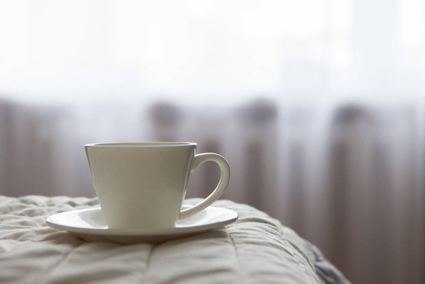 morning cup of coffee on the background of the bed and the window - Φωτογραφία, εικόνα
