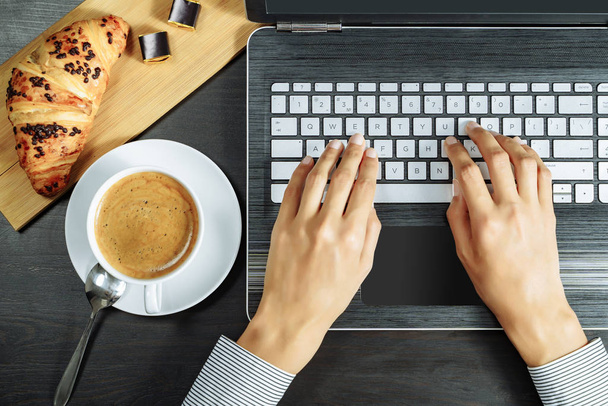 Kaffee, Croissant und weibliche Hände auf einer Laptop-Tastatur. Business-Frühstückskonzept. - Foto, Bild
