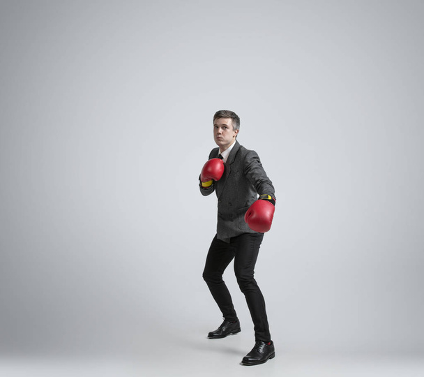 Caucasian man in office clothes boxing isolated on grey studio background - Фото, изображение