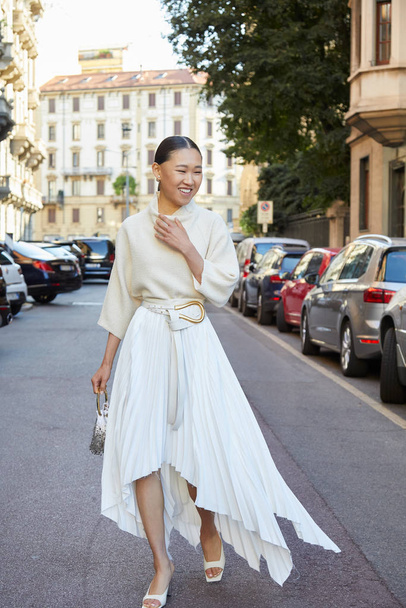 Woman with long pleated skirt and sweater before Salvatore Ferragamo fashion show, Milan Fashion Week street style  - Foto, Bild