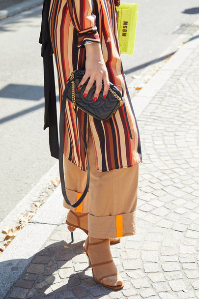 Woman with black leather Gucci bag and striped long shirt before Msgm fashion show, Milan Fashion Week street style  - Valokuva, kuva