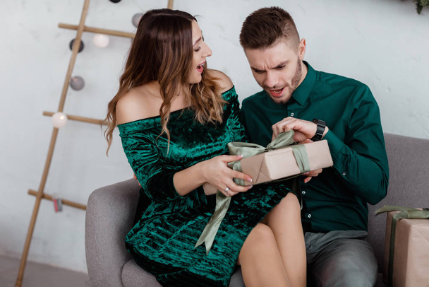 Opening christmas present. Couple in love happy enjoy christmas holiday celebration. Loving couple cuddle smiling while unpacking gift christmas tree background.What a surprise. - Photo, Image