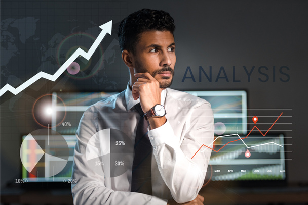pensive bi-racial trader looking away near charts, graphs and letters in office  - Photo, Image