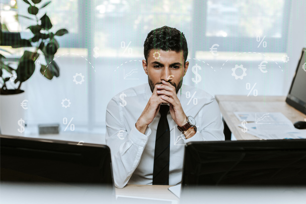 задумчивый двурасовый торговец смотрит на компьютеры в офисе
  - Фото, изображение