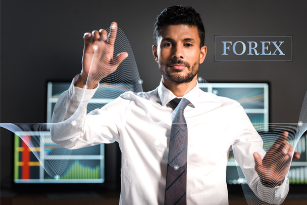 selective focus of bi-racial trader pointing with fingers near computers and forex letters - Foto, immagini