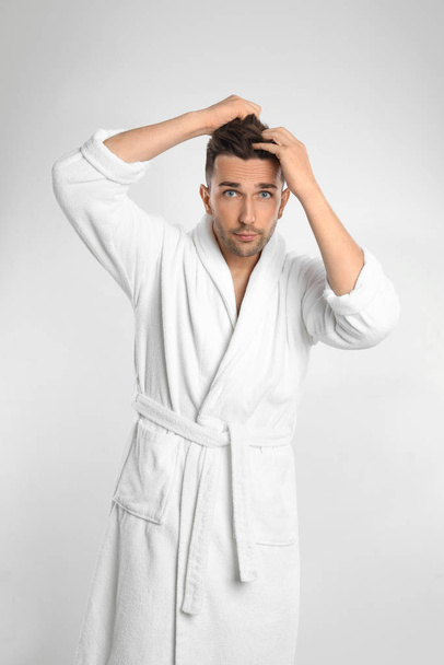 Young man in bathrobe on white background - Fotografie, Obrázek
