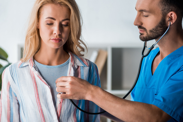 handsome bearded doctor examining woman with stethoscope  - Foto, imagen