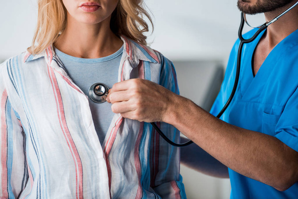 przycięty widok brodatego lekarza badającego kobietę stetoskopem  - Zdjęcie, obraz