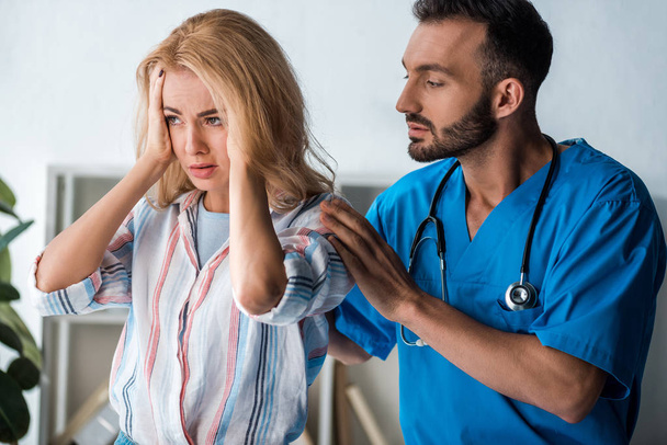 handsome doctor touching emotional woman with headache  - Foto, immagini