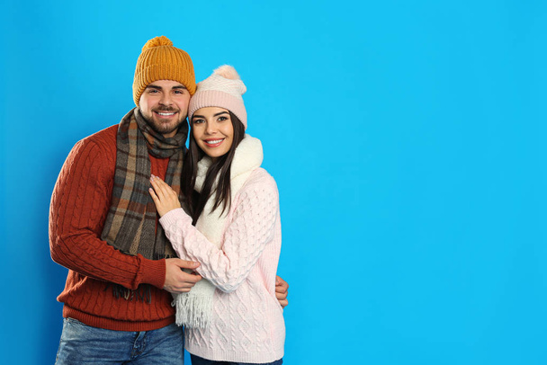 Happy young couple in warm clothes on blue background, space for text. Winter vacation - Foto, immagini