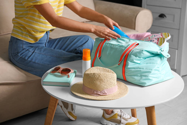 Woman putting items for vacation in bag indoors, closeup - Photo, image