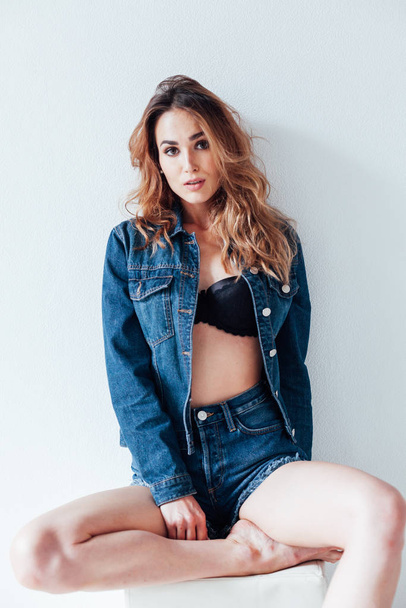 Portrait of a beautiful fashionable woman in jeans and black lingerie style - 写真・画像