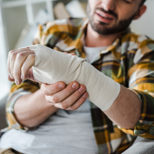 selective focus of injured hand of man in bandage  - Foto, Imagem
