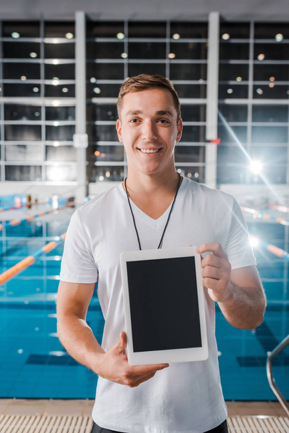 entrenador sonriente sosteniendo tableta digital con pantalla en blanco
  - Foto, Imagen