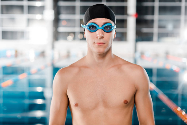 handsome swimmer in goggles and swimming cap looking at camera  - Photo, Image
