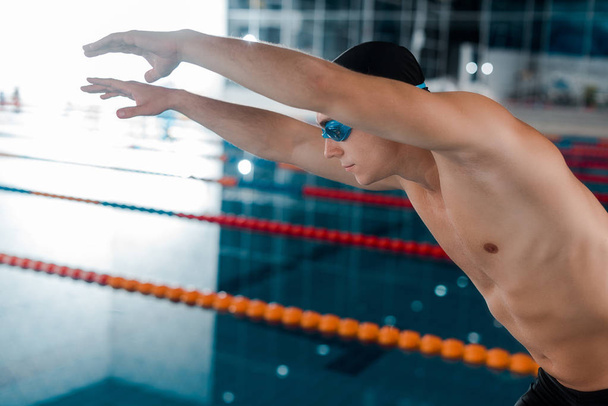 όμορφος και μυώδης κολυμβητής σε γυαλιά με απλωμένα χέρια  - Φωτογραφία, εικόνα