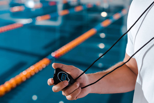 cropped view of trainer holding timer near swimming pool  - Valokuva, kuva