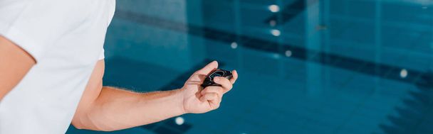 panoramic shot of sportsman holding timer near swimming pool  - Photo, Image