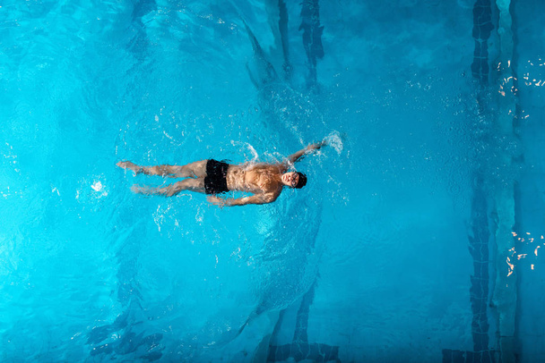 top view of sportsman in swimming trucks training in swimming pool  - Foto, afbeelding