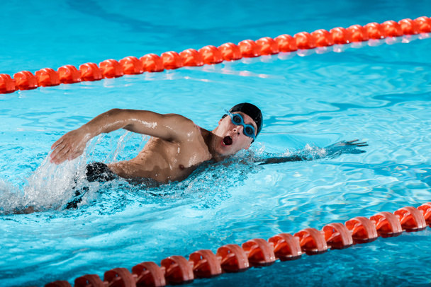 gotas de agua cerca de nadador con entrenamiento bucal abierto en piscina
  - Foto, imagen