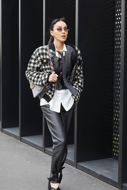 Woman with black leather trousers and houndstooth black and white jacket before Gucci fashion show, Milan Fashion Week street style  - Foto, imagen
